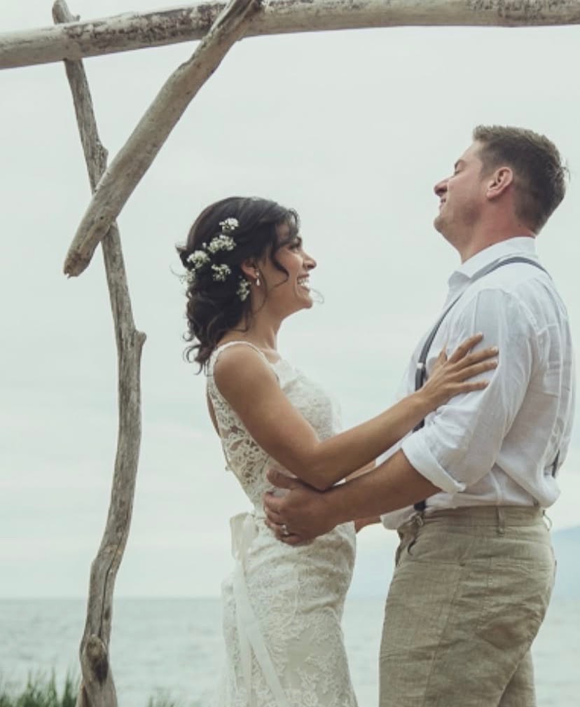 Couple laughing under driftwood arch
